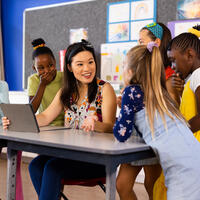 Diverse female teacher with tablet and elementary schoolgirls in class