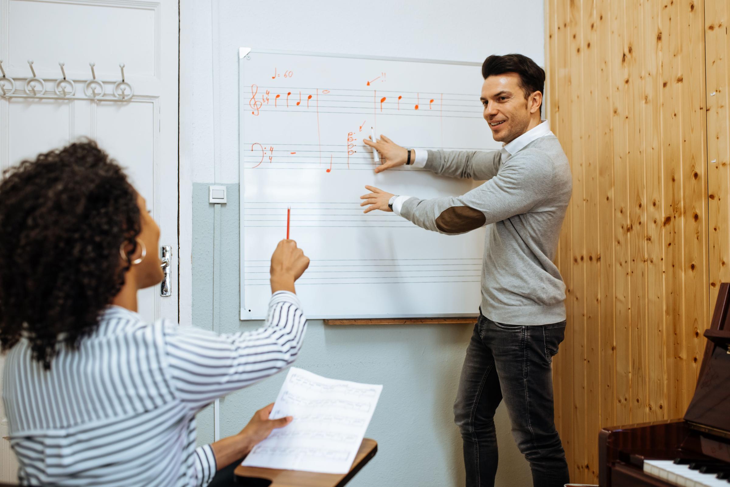 Man teaching woman music notes